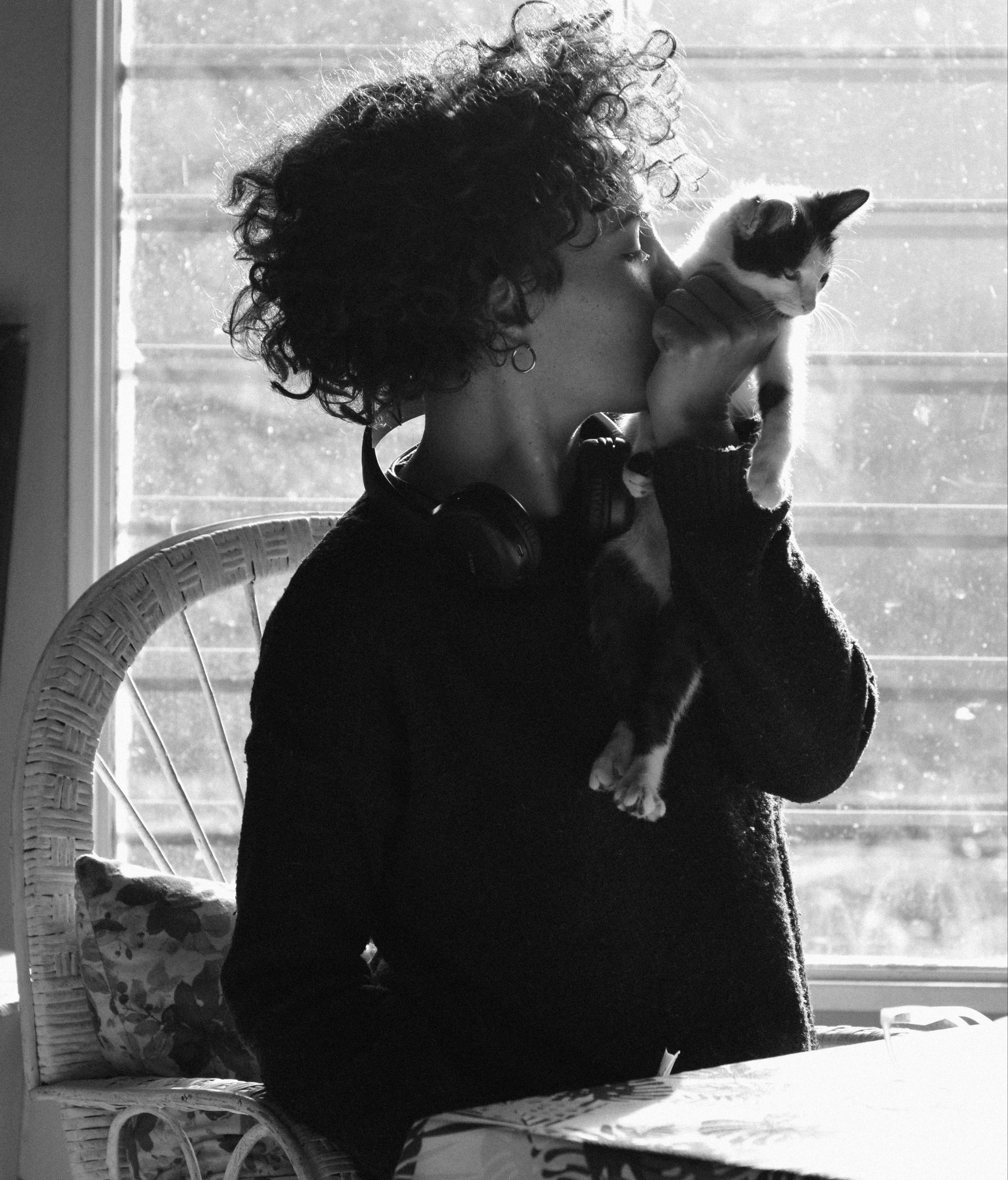 Photograph of a woman holding a kitten and kissing its neck